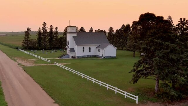 Low rising aerial flyover of a small country church at sunset in South Dakota, USA.