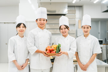 野菜を持つコックコート姿のシェフ・コック・調理師の男女
