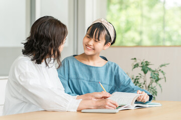 Fototapeta premium 母親・教師・家庭教師・塾講師に勉強を教えてもらう中学生の女の子 