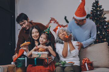 Portrait of Asian family exchanging presents during christmas at home. Attractive happy people holding gift box, celebrate holiday thanksgiving, xmas eve tradition in living room in house together.