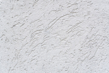 A close-up view reveals a textured wall surface. The plaster, likely stucco, exhibits a rough and weathered appearance with a subtle interplay of light and shadow.