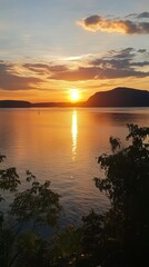 Obraz premium Golden Sunset Over Calm Water With Distant Hills