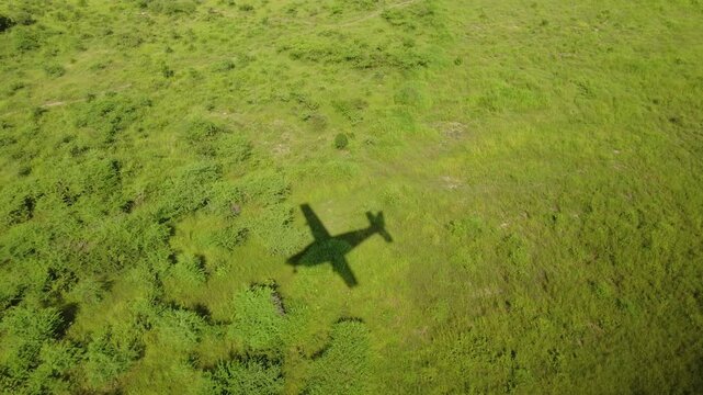 The expanding shadow of a small airplane passes over the grassland of South Sudan, Africa.