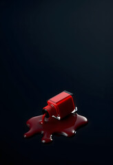 Naklejka premium Spilled Red Nail Polish Bottle on Dark Background - Beauty