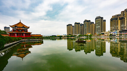 Obraz premium Skyscraper-City in the background and a Buddhist temple with a bridge over the lake in Yunnan Province