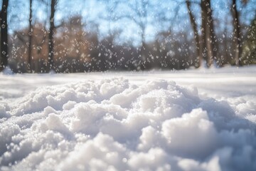 Close-up of snowy ground with falling snow and blurred trees in background.