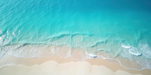 Aerial view of turquoise ocean waves gently lapping on a pristine white sandy beach 