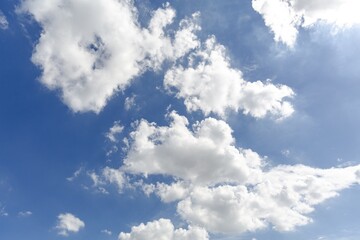 Bright blue sky with fluffy white clouds scattered across a sunny afternoon