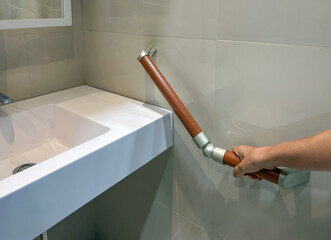 Senior woman holding on handrail for safety in bathroom