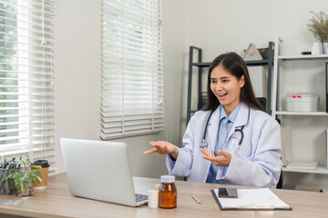 Confident Female Doctor Engaged in Virtual Consultation in Modern Medical Office Setting with Laptop and Medical Equipment