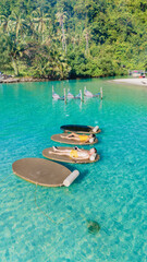 Obraz premium Under the warm sun, people enjoy leisure time on floating loungers amidst the clear turquoise waters of Koh Kood Thailand. Surrounded by lush greenery, the tranquil atmosphere invites relaxation.