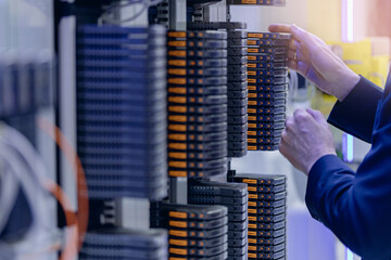 Male technician organizing network servers in data center, close-up view