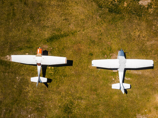 Two single-engine airplanes parked on grass field aerial view