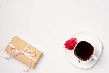 Gift box and mug of coffee with rose on white background . Flat lay, top view. Copy space