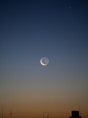 Obraz premium Tokyo,Japan - December 29, 2024: Rising Crescent moon with earthshine at winter dawn