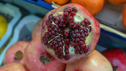 A close-up of a sliced pomegranate showcasing its juicy seeds, set against a softly blurred market...