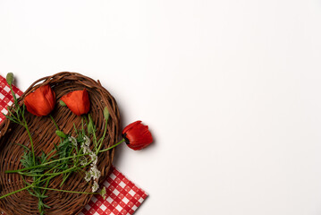 Wild flowers in a wicker basket on a white background. Flat lay, top view. Copy space