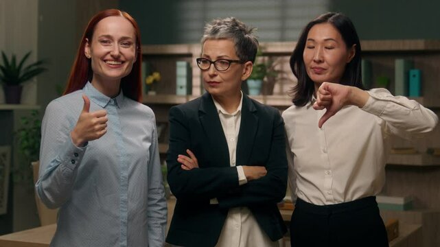 Three women showing thumbs up down gesture unsure unknown doubt choice employees office yes or no refusal approval question decision businesswomen business females girls positive negative boss choose