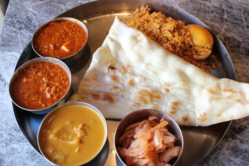 Indian cuisine: curry lunch plate (chicken keema curry, seafood curry, achar, naan and egg biryani)