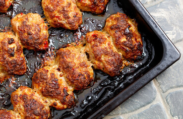 A tray of meat is cooked in a pan