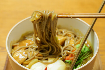 Trying to eat freshly made warm Japanese curry soba noodles with chopsticks.