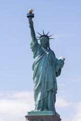 Closeup of the Statue of Liberty on the Liberty Island in New York against a blue sky and clouds.