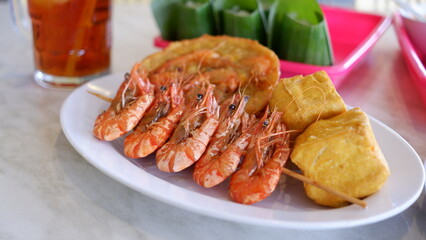 Shrimp satay on a white plate.