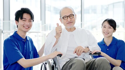 Obraz premium 介護士とグッドサインをする車椅子の高齢者