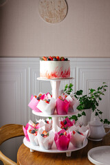 wedding cake on a stand with cupcakes