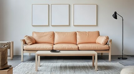 Light peach leather sofa, wooden coffee table, three blank frames, floor lamp, and rug in a minimalist living room.