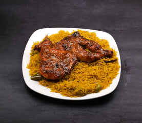 Honey glazed fried chicken majboos rice in a white ceramic plate in a dark background