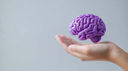 Purple day for epilepsy awareness concept. hand holding purple brain model against plain background