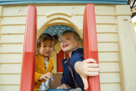 Preschool Children Looking Out Window in Backyard Playhouse