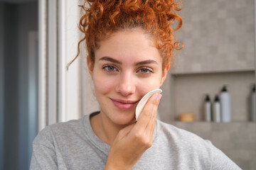 Woman uses reusable makeup remover pad, embrace sustainable beauty