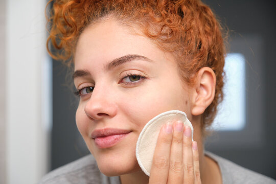 Young woman cleaning her face with a reusable makeup remover pad
