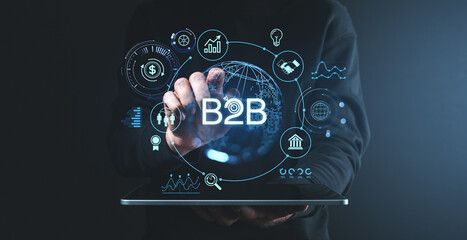 B2B concept with digital icons and data visualization on screen in hands of a person, on dark background.