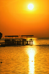 Fototapeta premium Fantastic sunrise in Marsa Alam over the Red Sea. visible palm trees, beach umbrellas, typical hotel buildings. Egypt, Marsa Alam 2024