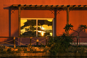 Reflection in the window of a hotel room - the rising sun, beach umbrellas, a fragment of a jetty leading to a coral reef. Egypt 2024