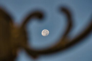 Full moon seen between the metal ornaments of a lamp.