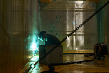 Fototapeta premium Skilled welder creating sparks in dimly lit industrial space