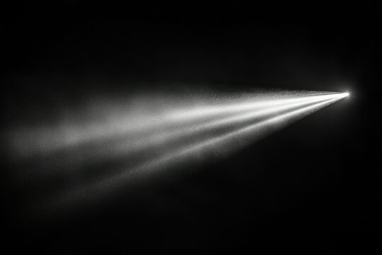A bright beam of light emanating from a point source, dispersing into a fine spray of particles against a dark background.