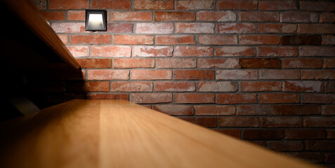 Drewniany stopień oświetlonych schodów, ściana z czerwonej cegly © Paweł Kacperek