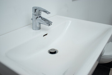 Close up of a bathroom faucet with limescale stains and dirty sink