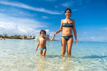 Naklejka premium A woman and a child are walking in the ocean