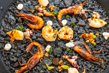 Delicious black rice paella with grilled shrimps and squid in mallorca