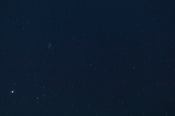 A winter night sky full of twinkling stars. Pleiades Cluster and Jupiter