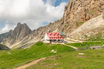 View of the Tierser Alpl mountain hut (Rifugio Alpe di Tires) during summer. some people on the...