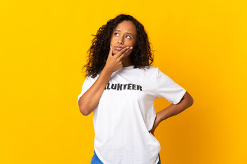 Teenager cuban volunteer girl isolated on yellow background having doubts