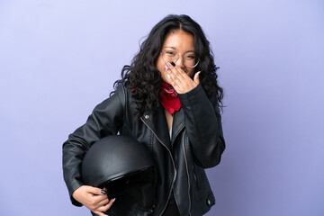 Young asian woman with a motorcycle helmet isolated on purple background happy and smiling covering mouth with hand