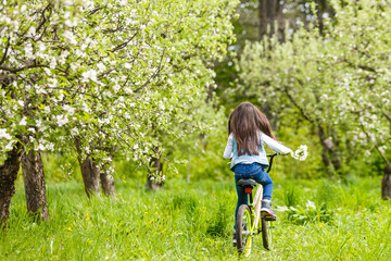 little girl with a bicycle near a flower